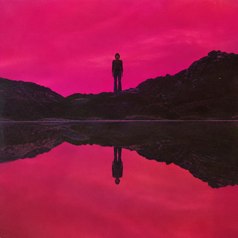 A figure reflected upside-down in a magenta lake